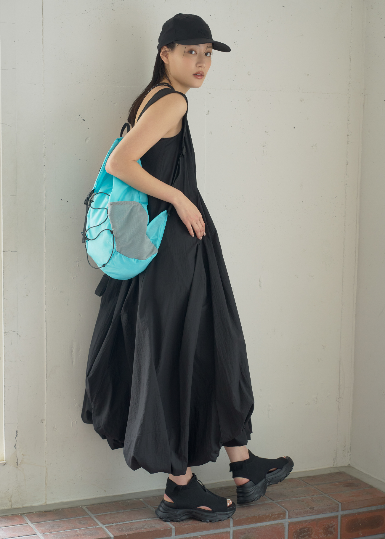 シアーナイロンボリュームワンピース・emmiロゴシアーキャップ・【限定カラー】パッカブルバックパック・eco ニットサンダルを着用した女性