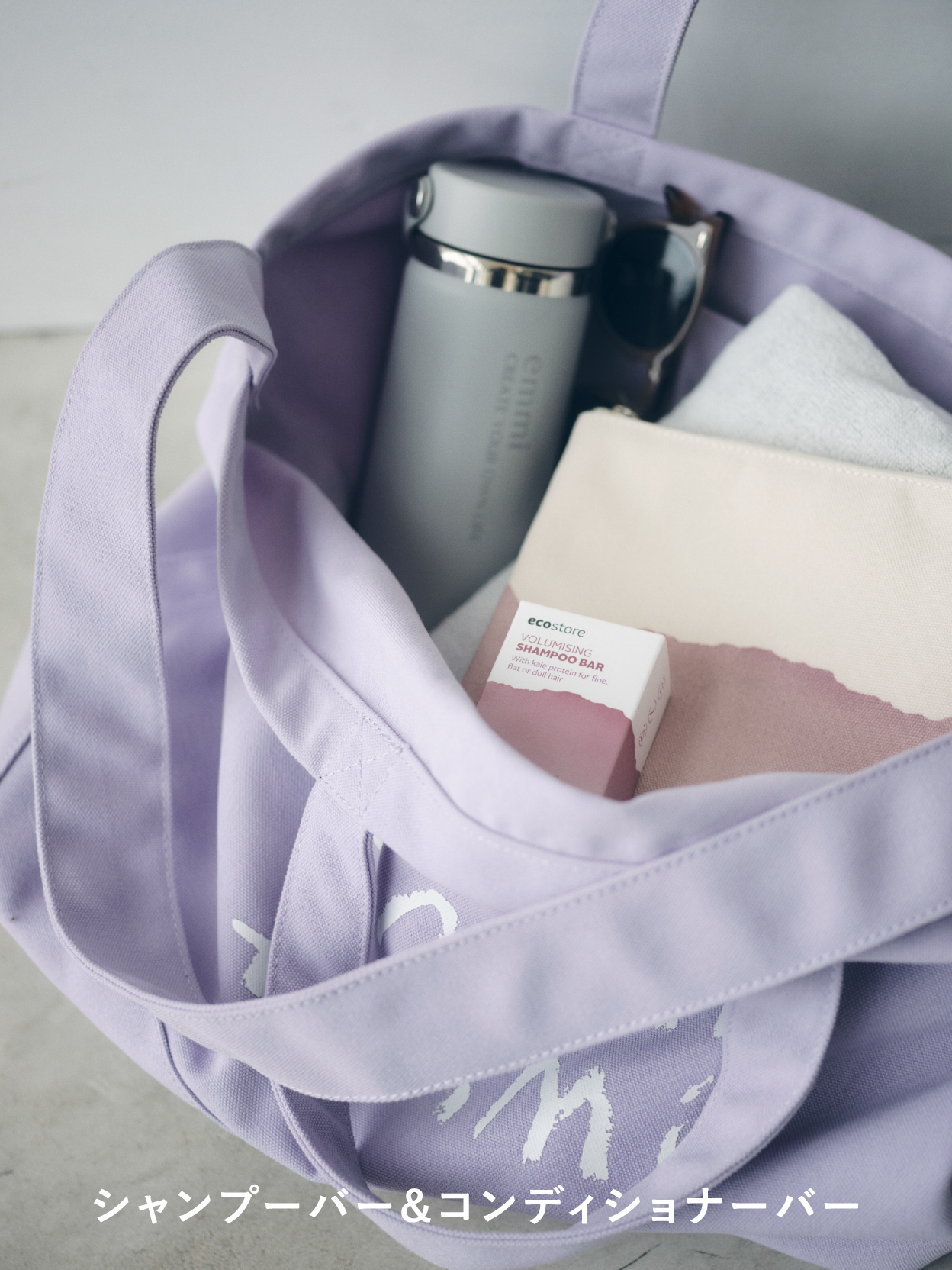 【emmi×ecostore】eco キャンバストート・【emmi×ecostore】eco フラットポーチ・【emmi×HydroFlask】16oz Wide Mouth・アセテートベーシックサングラスを着用した女性