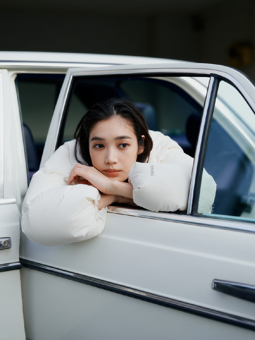 白いクロップドフォルムダウンを着用して車に乗ってる女性