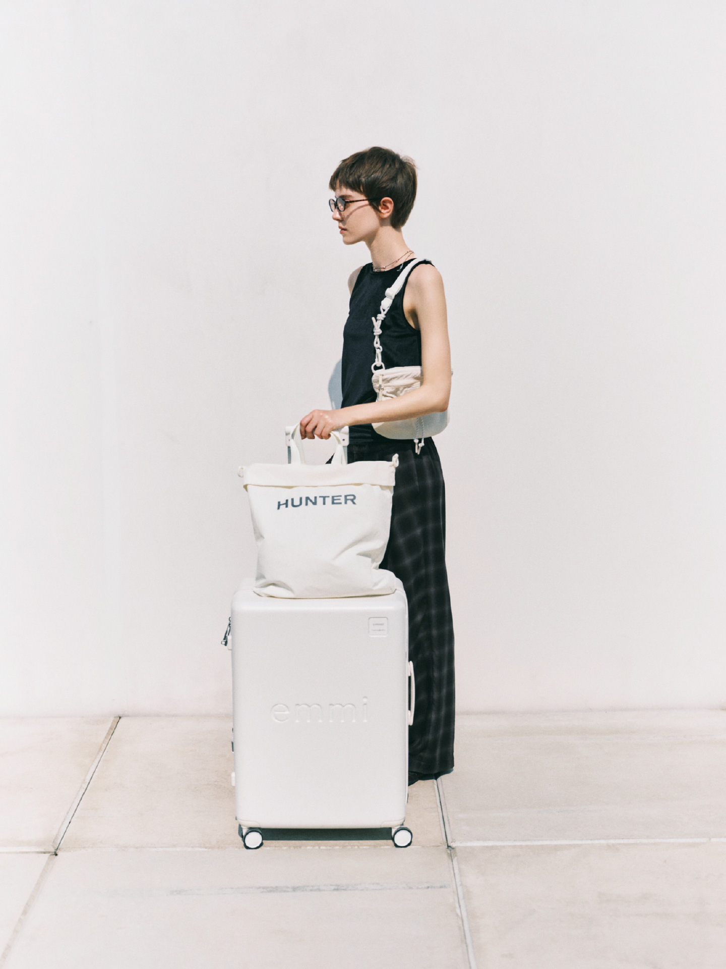 白色の【emmi×HUNTER】トートと【emmi×Samsonite】スピナー65を着用したモデル画像