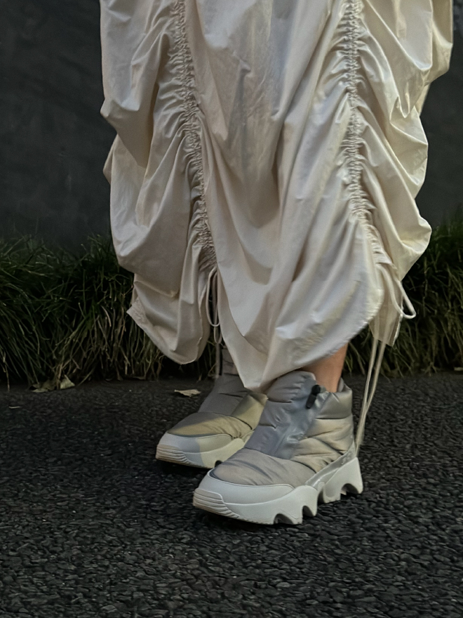 シャギーテーラードジャケットコート・eco ボリュームギャザースカート・【SOREL for emmi】IMPACT PUFFY ZIP WPを着用した女性の足元