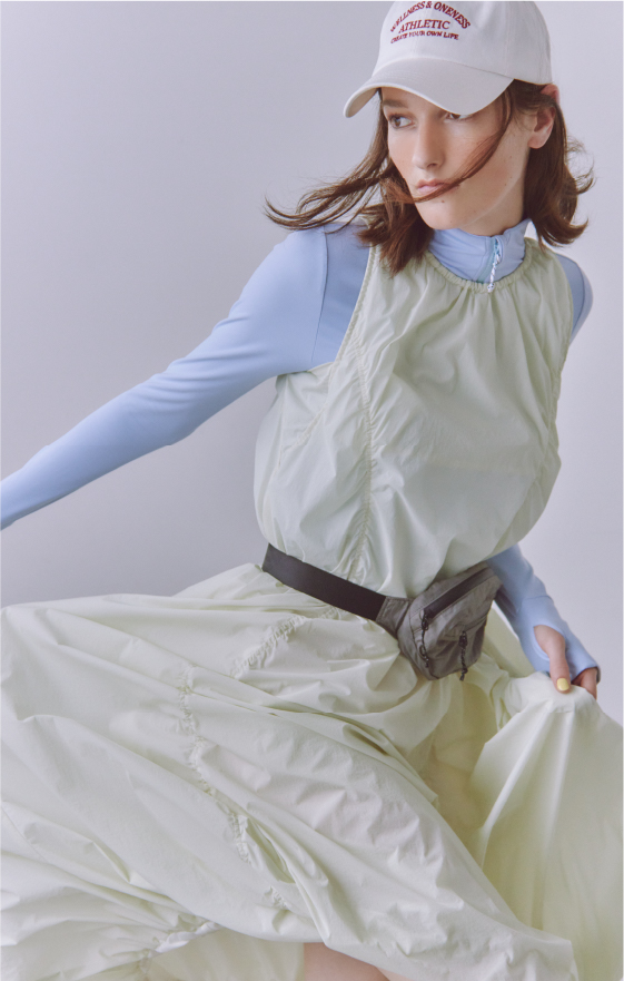 ナイロンバルーンワンピース・サステナレッチUnity ジャケット・エンブロイダリーキャップ・NYLON HIPBAGを着用した女性