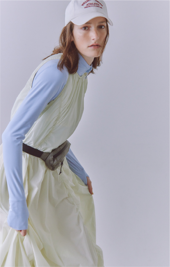 ナイロンバルーンワンピース・サステナレッチUnity ジャケット・エンブロイダリーキャップ・NYLON HIPBAGを着用した女性