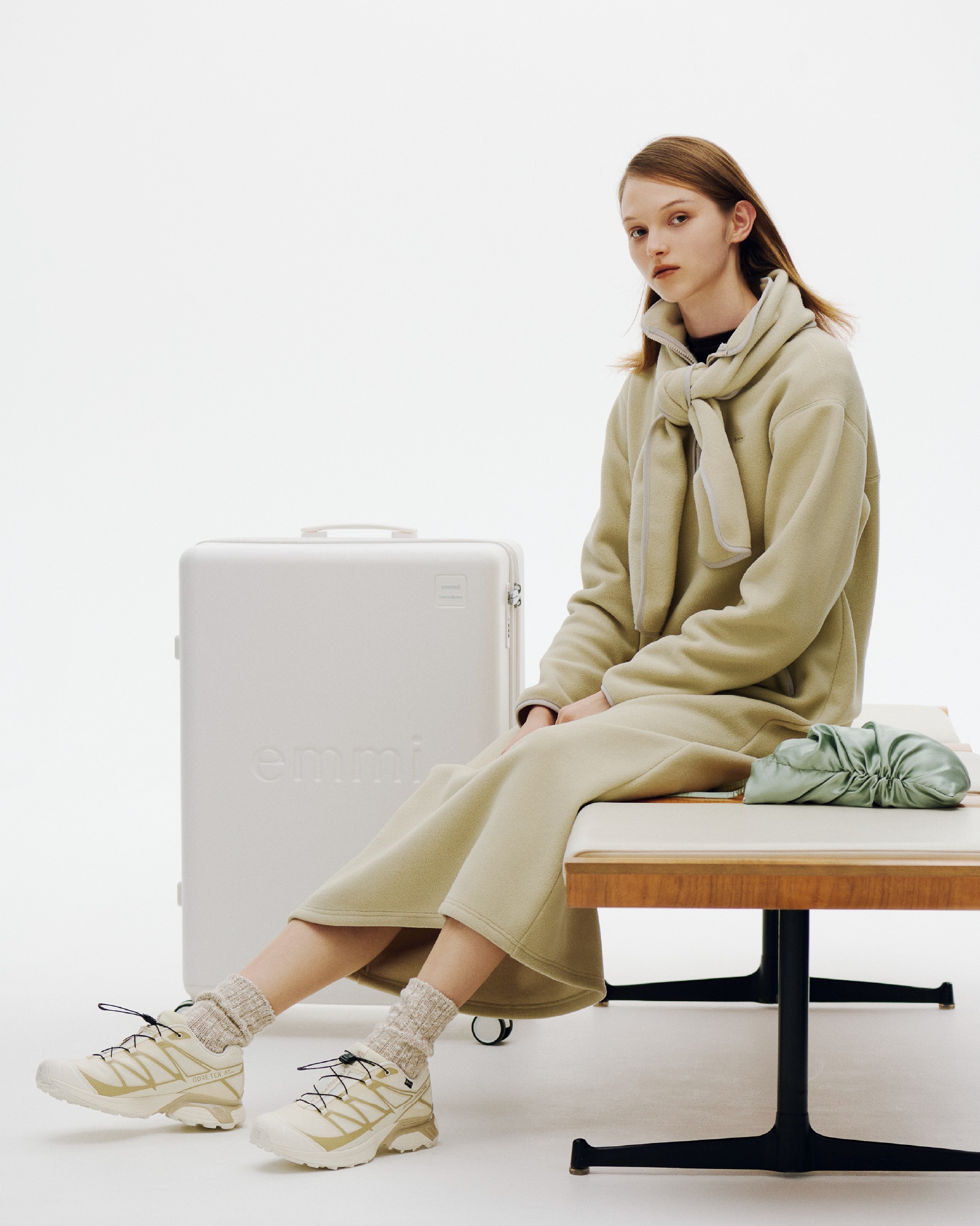 ミントのeco ストール付きフリースワンピースとHOLIDAY GIFT SET（バッグ）、アイボリーのXT-PATHWAY GTX（シューズ）を着用し、ベンチに座る女性のビジュアル