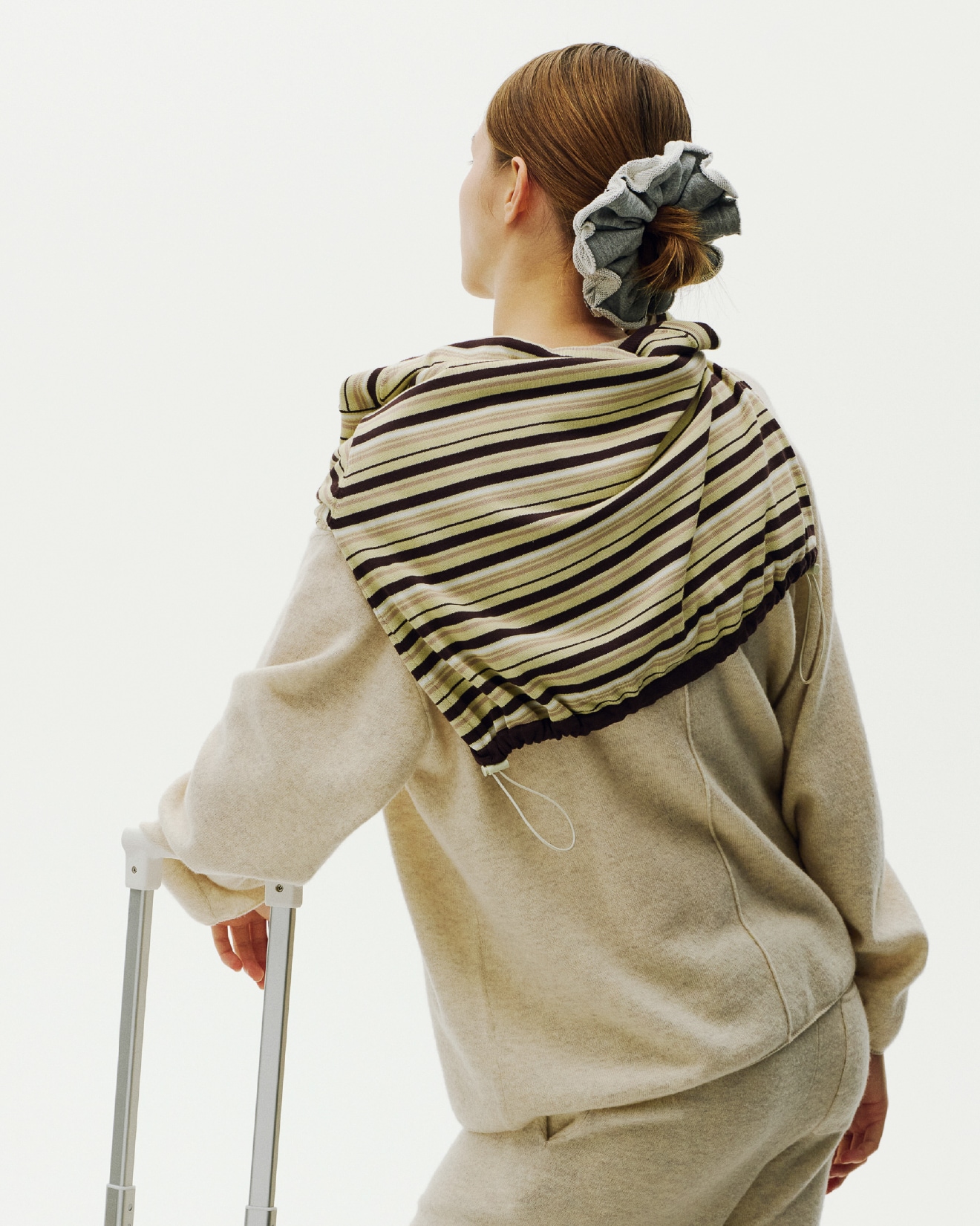 ライトベージュのラムウールオーバーニットトップス・イエローの ボーダーニットとグレーのスウェットシュシュを着用した女性の後ろ姿