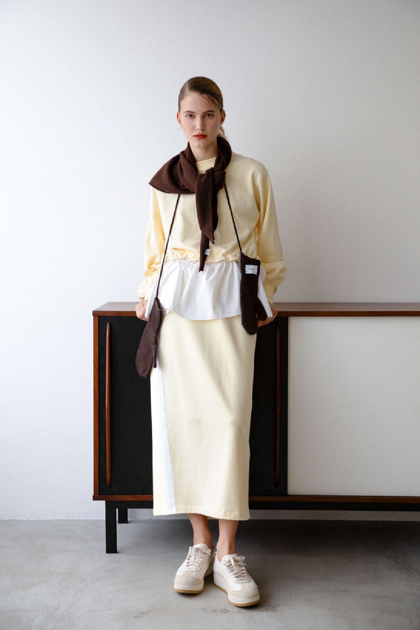 イエローの布帛ドッキング裏毛セットアップ・ブラウンのウールニットトライアングルスカーフ・ブラウンのマルチユースミトン・クリームのMEXICO 66 CHUNKを合わせたコーディネート