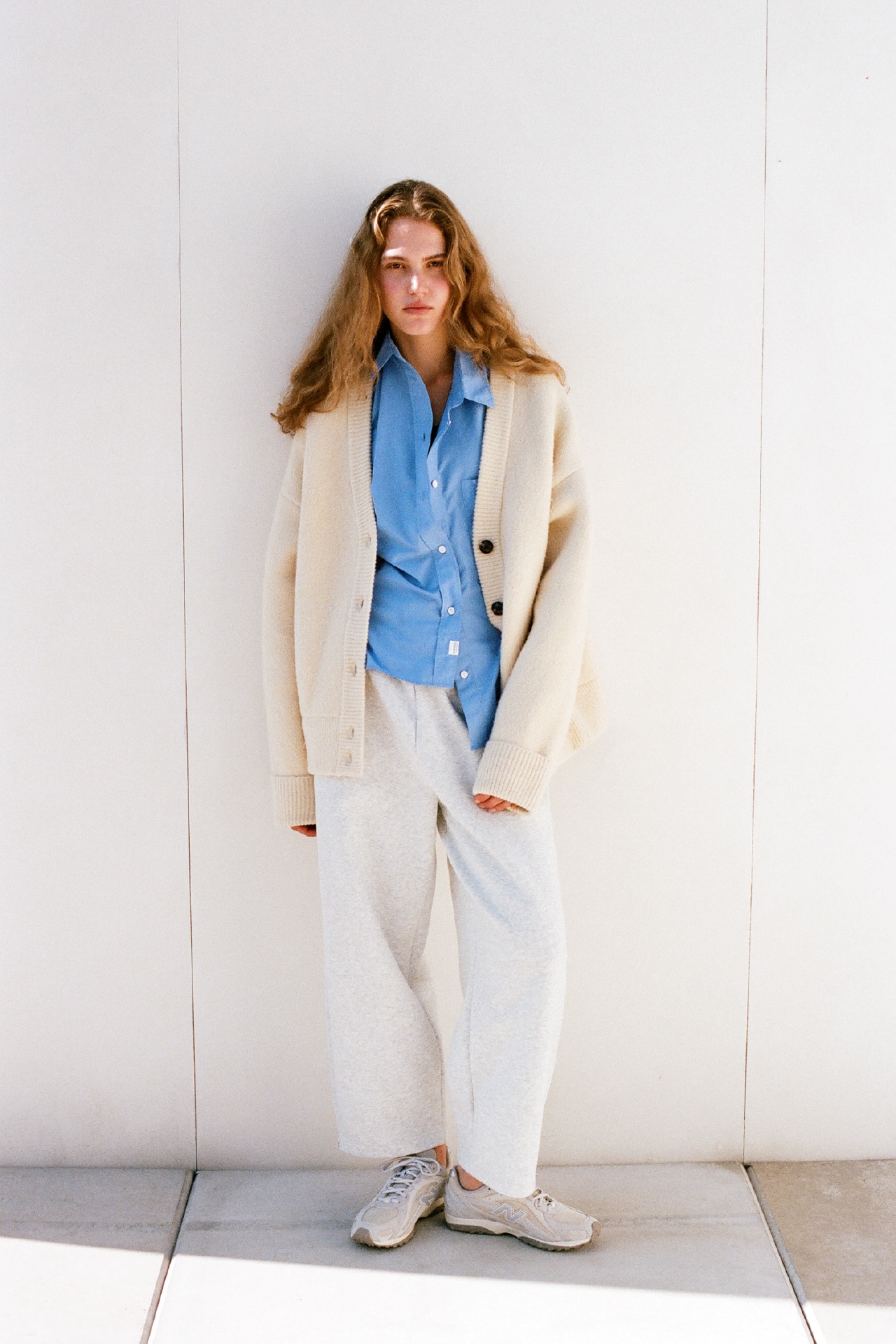 イエローのVネックニットカーディガン・ブルーのemmiロゴ刺繡シャツ・黒のシアーハーフトップブラ・リニアヘリテージフリースバレルパンツを合わせたコーディネート