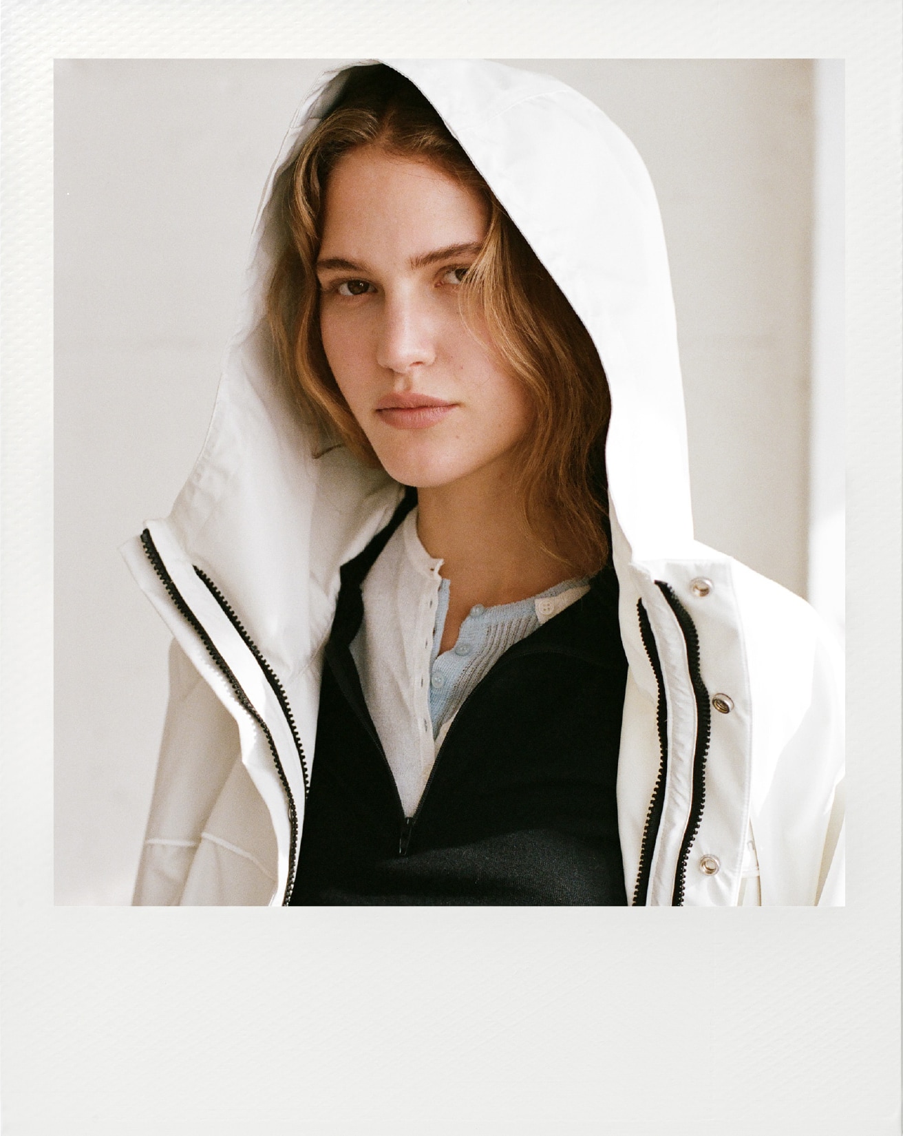 オフホワイトのフリースライナー付きユーティリティコート・黒のウールパーカートップス・白のヘンリーネックレイヤードニットトップス・白のフラワーチュールスカートを合わせたバストアップ写真