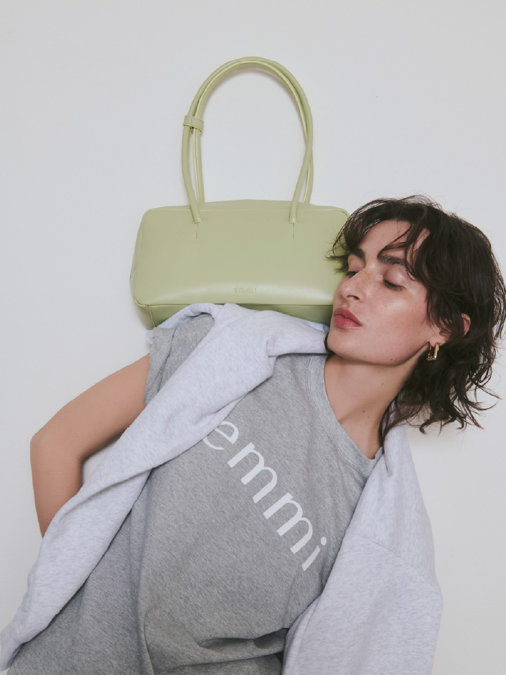 【ONLINE限定カラー】eco emmiロゴTシャツ/UVカット、Vネックスウェットプルオーバー【セットアップ対応】、レザーボストンバッグ、ロングワンタッチピアスを着用したモデル画像