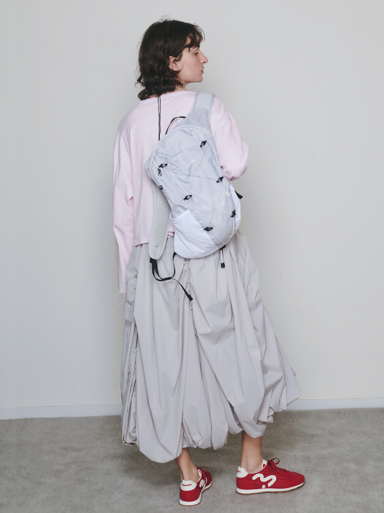 emmiロゴクルーネックロングTシャツ、ドロストバルーンスカート/撥水、サテンコードネックレス、【USAGI ONLINE・ZOZO限定カラーあり】パッカブルバックパック/撥水、【em】ソフトランニングスニーカーを着用したモデルの後ろ姿