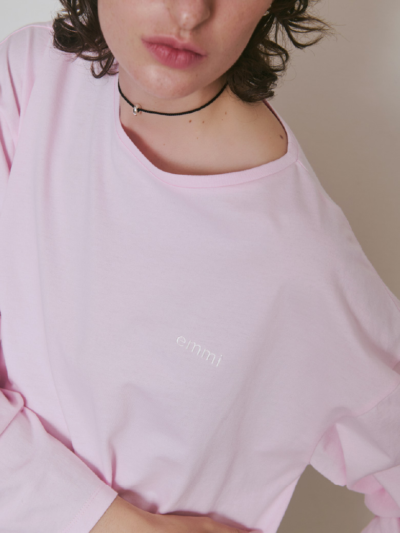 ピンク色のemmiロゴクルーネックロングTシャツとサテンコードネックレスの着用イメージ