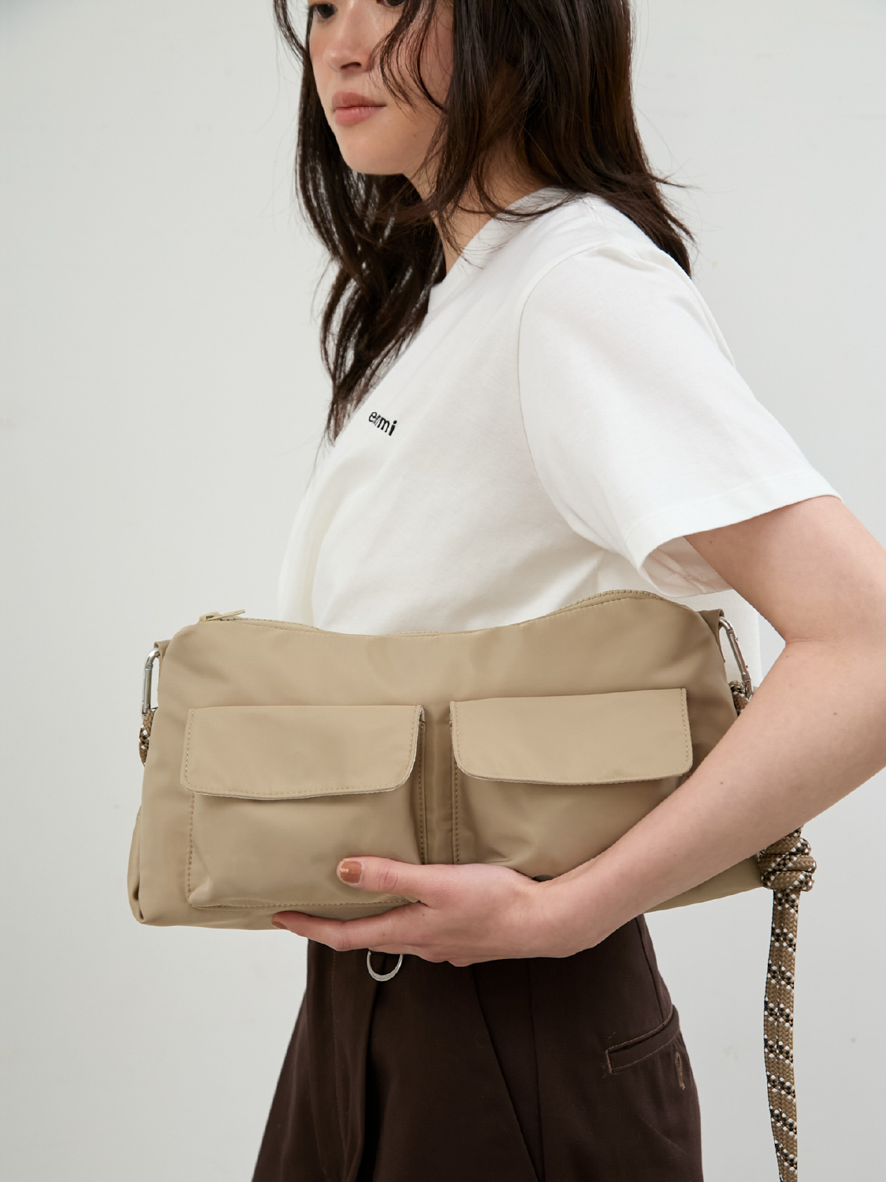 白色のemmiロゴ裾タックデザインTシャツ、【Dickies(R)×emmi】タックワイドパンツ、【ONLINE限定カラーあり】ギャザーショルダーコードバッグを着用したモデル画像