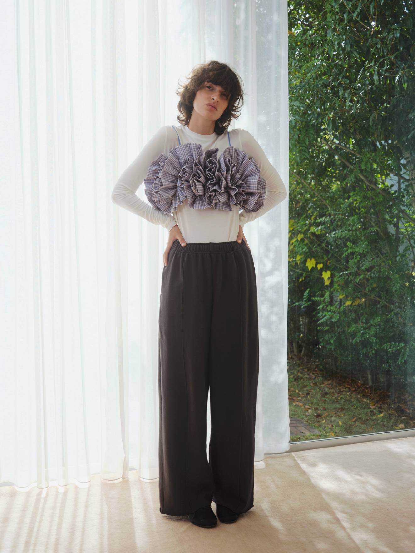 サックスのチェックフリルビスチェ【セットアップ対応】・白のバンブーロングスリーブカットソー・黒の2タックワイドパンツ【セットアップ対応】・イエローのシアーハイソックス・黒のSpeed cat satin emmiを合わせた、愛らしいディテールが心をくすぐるコーディネート