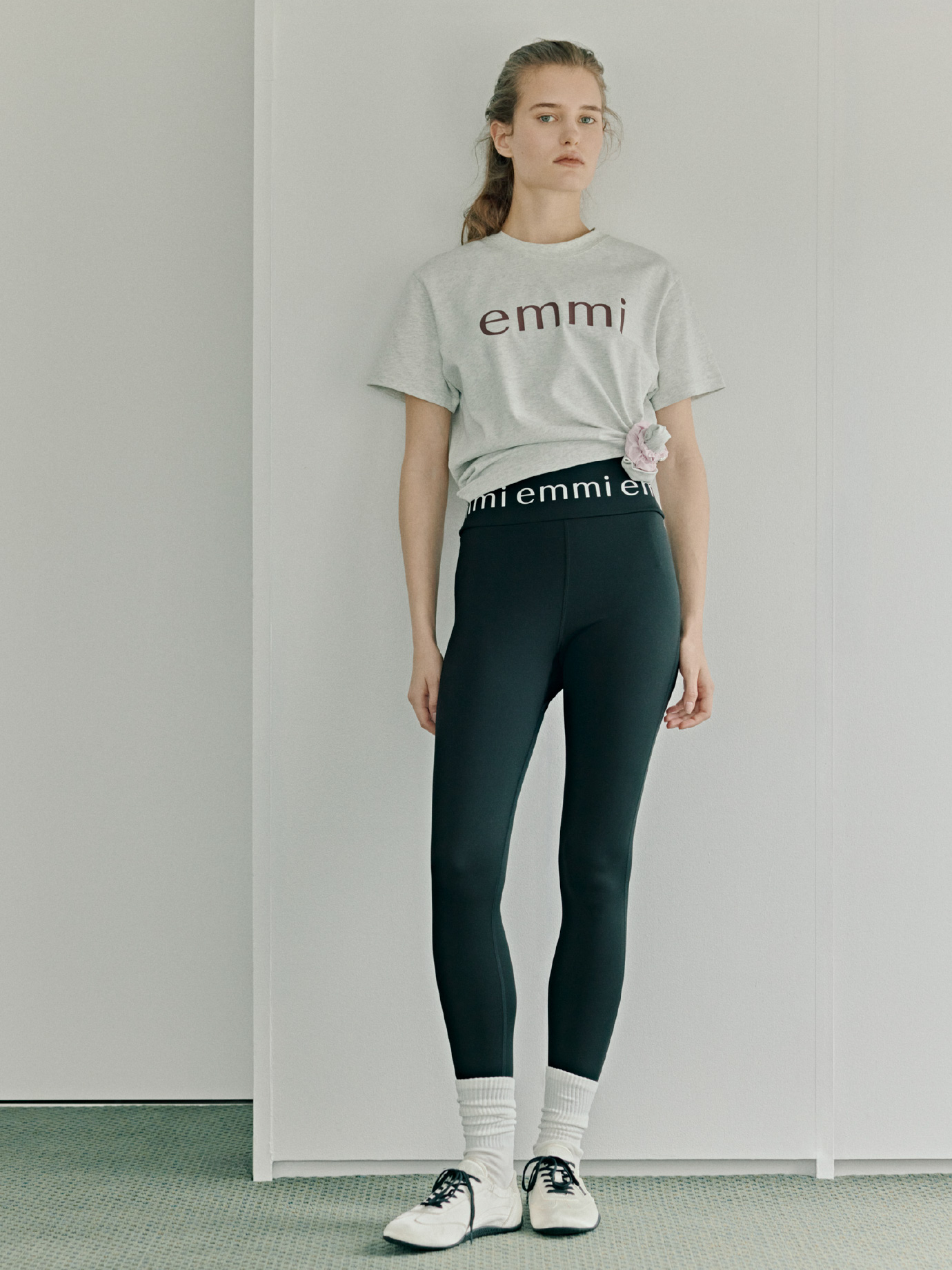 ベーシックemmiロゴTシャツ、emmiロゴレギンス、【em】サテンスニーカーを着用した女性のイメージ