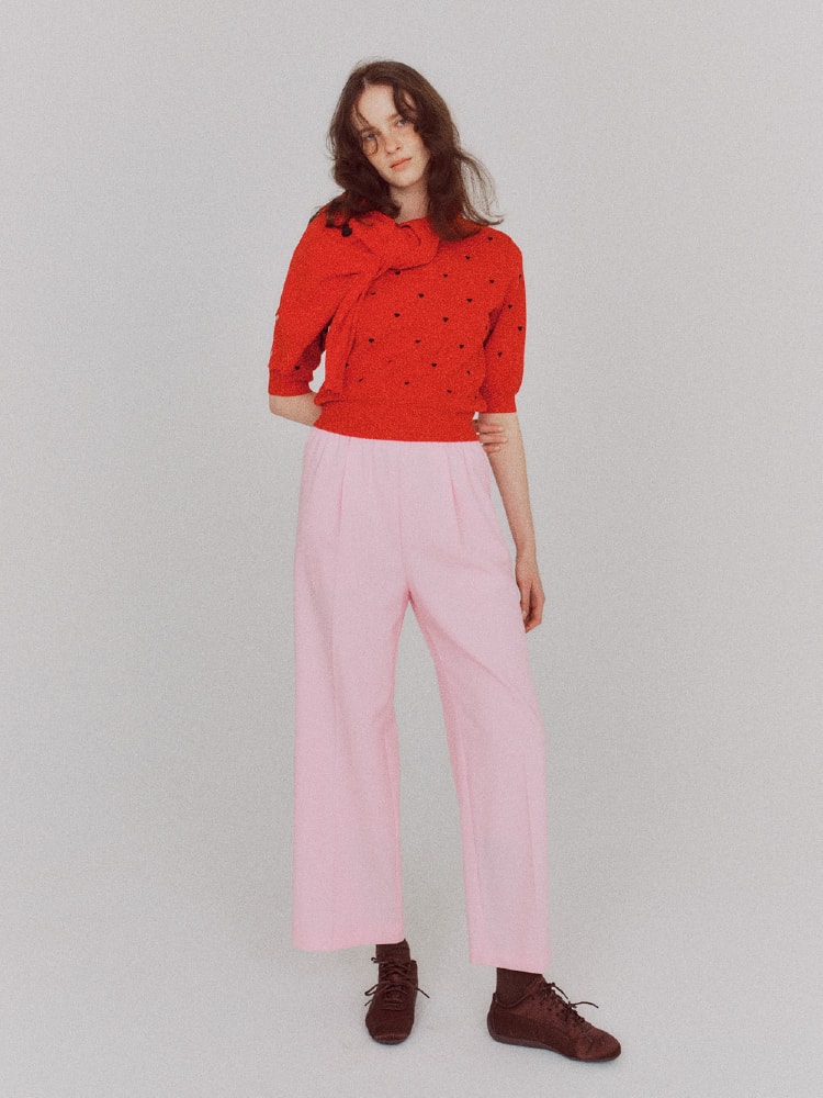 赤いトップスにピンクのパンツを履いた女性の画像