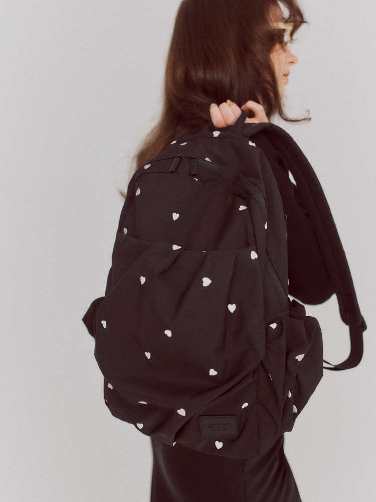ハート柄の黒いリュックサックを持った女性の画像