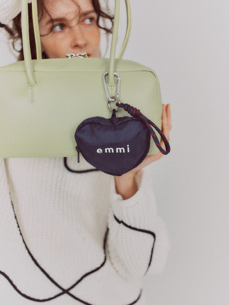 ハート型のエコバックを付けた薄緑のバッグを持った女性の画像