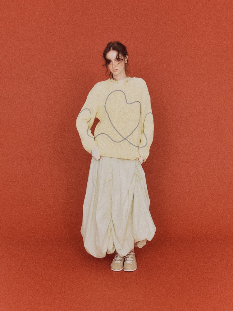 パステルイエローのトップスにロングスカートを着た女性の画像