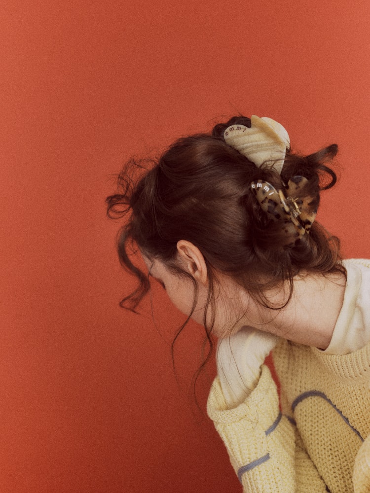 髪を止めてパステルイエローのトップスを着た女性の画像