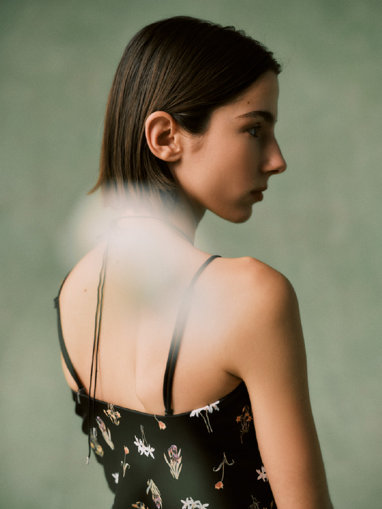 ハート柄のネイビーのトップスを着て腰に白いシャツを巻いた女性の画像