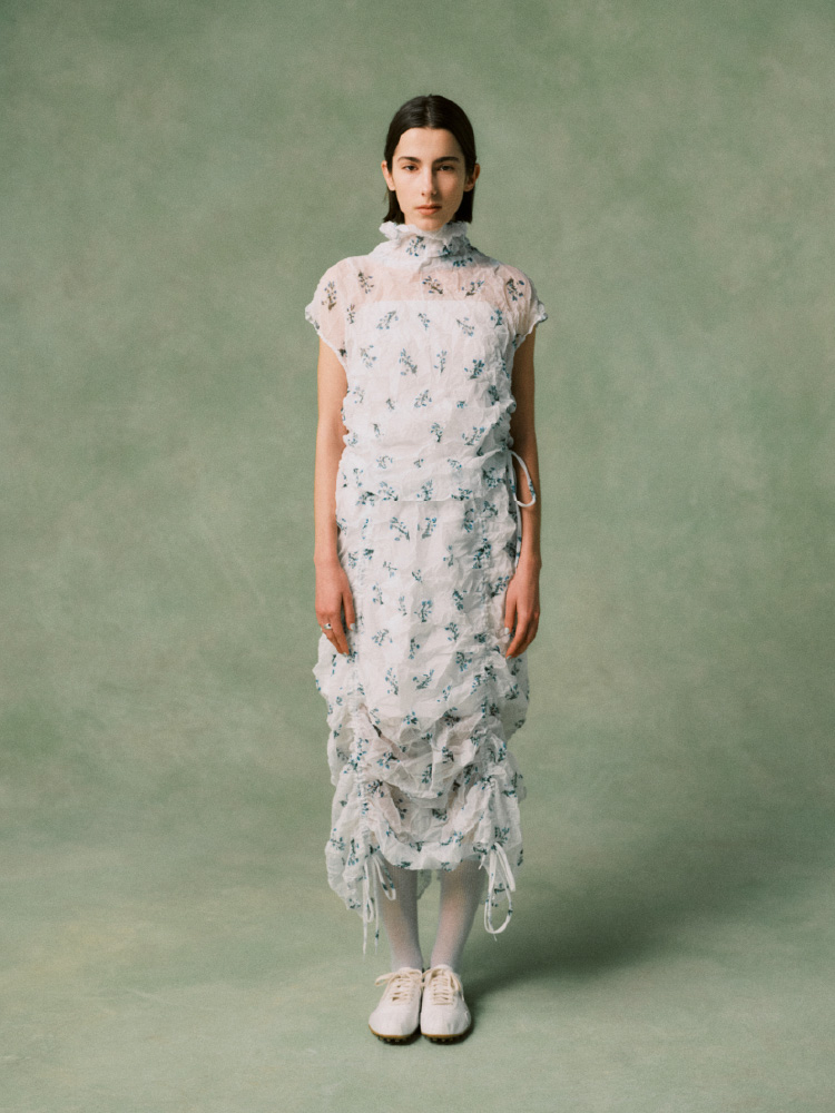 ハート柄のネイビーのトップスを着て白いシャツを首にかけた女性の画像